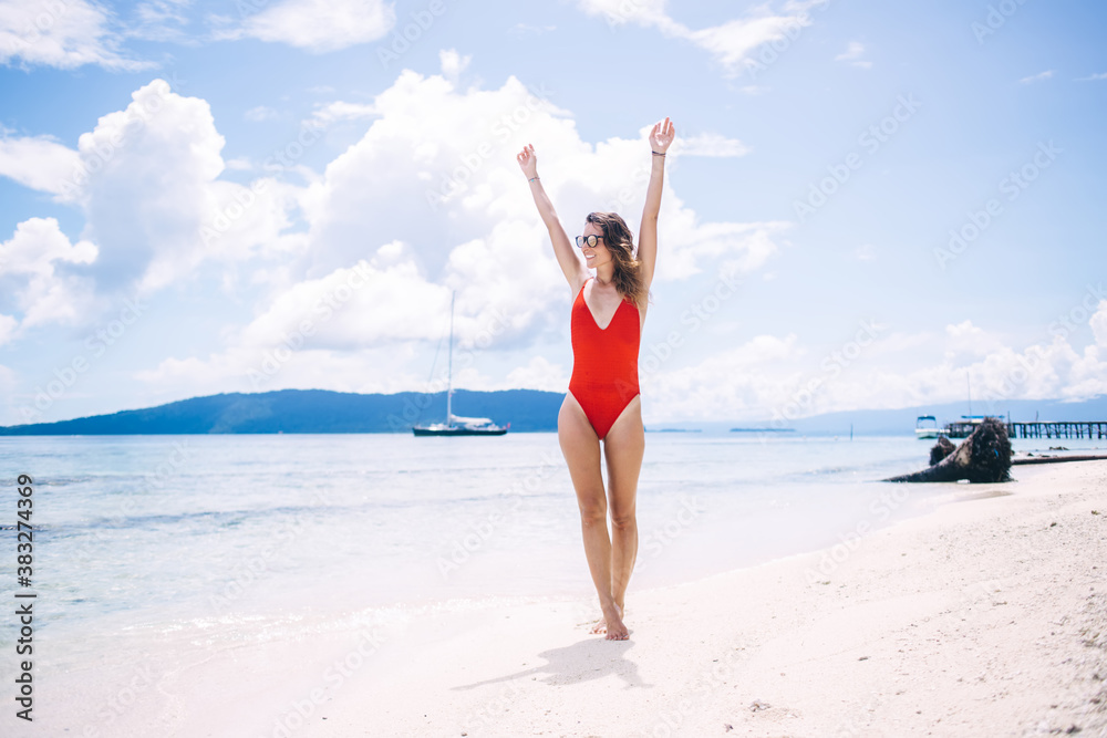 Carefree woman raising hands feeling good during summer vacations for visiting paradise place with perfect seashore and tropical beach, happy female swimmer enjoying time on Seychelles island