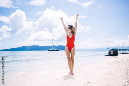 Carefree woman raising hands feeling good during summer vacations for visiting paradise place with perfect seashore and tropical beach, happy female swimmer enjoying time on Seychelles island