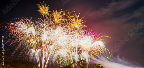 A low angle shot of many fireworks in groups at night. There is dazzlingly lit and colorful. Feeling fun and happy. The idea for celebration wallpaper with copy space on the right of the picture.