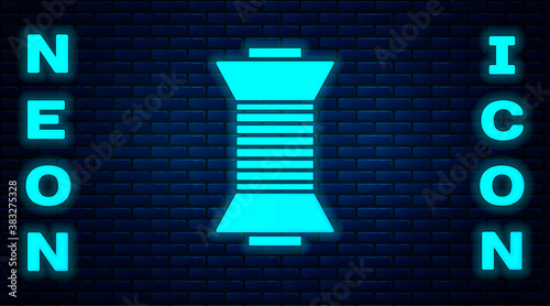 Glowing neon Sewing thread on spool icon isolated on brick wall background. Yarn spool. Thread bobbin. Vector Illustration.