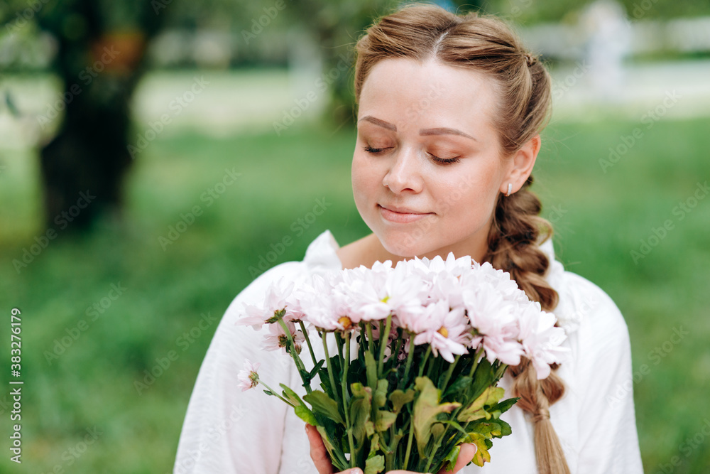 Beautiful girl with closed eyes sniffs beautiful white flowers outdoors Beautiful girl with closed eyes sniffs beautiful white flowers outdoors