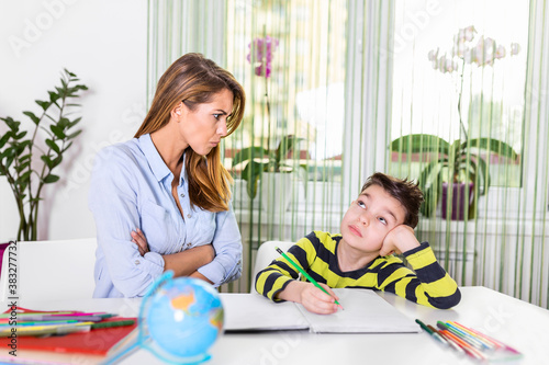 Child having problem with concentration while doing homework. Stressed Mother and Son Frustrated Over Failure Homework, School Problems Concept. Mother help her is son make difficul homework photo