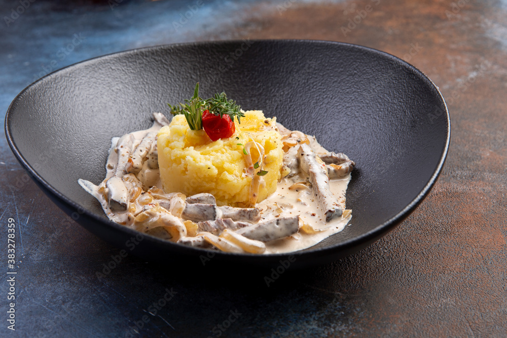 Beef stroganoff with mashed potatoes in a dark plate Beef stroganoff with mashed potatoes in a dark plate
