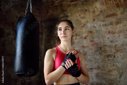 Young woman ready for hits punching bag during a boxing training. Female boxer doing fitness.