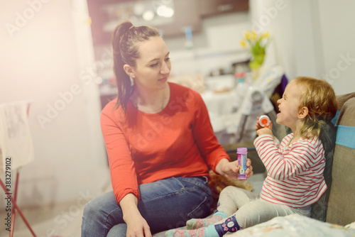 Happy mother and daughter in the park. Beauty nature scene with family outdoor lifestyle. Happy family resting together on the green grass, having fun outdoor. Happiness and harmony in family life