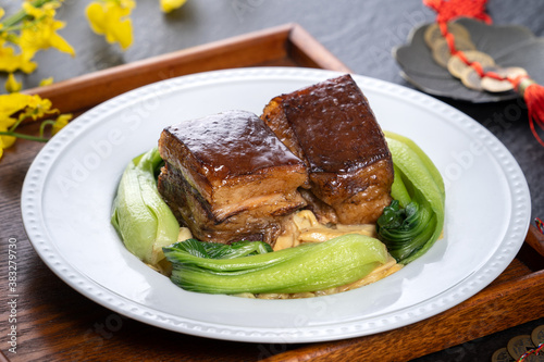 Dong Po Rou (Dongpo pork meat) in a beautiful plate with green vegetable, traditional festive food for Chinese new year cuisine meal, close up. photo