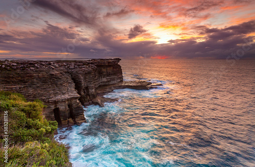 Sunrise over the ocean and the crumbling headland cliffs