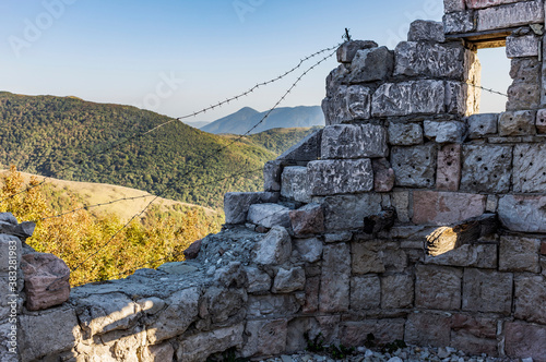 Фотография Old military dilapidated fortress on the background of a mountain pass in autumn