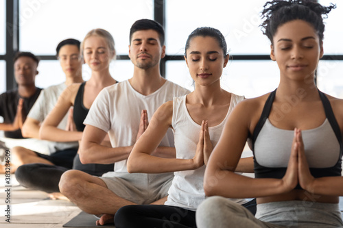 Mind Harmony. Group of young sporty yoga lovers meditating together in studio photo