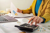 Woman accountant use calculator and computer with holding pen on desk in office. finance and accounting concept