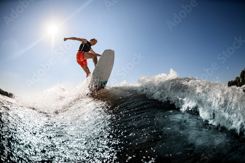 Active man rides on surf style wakeboard on the wave