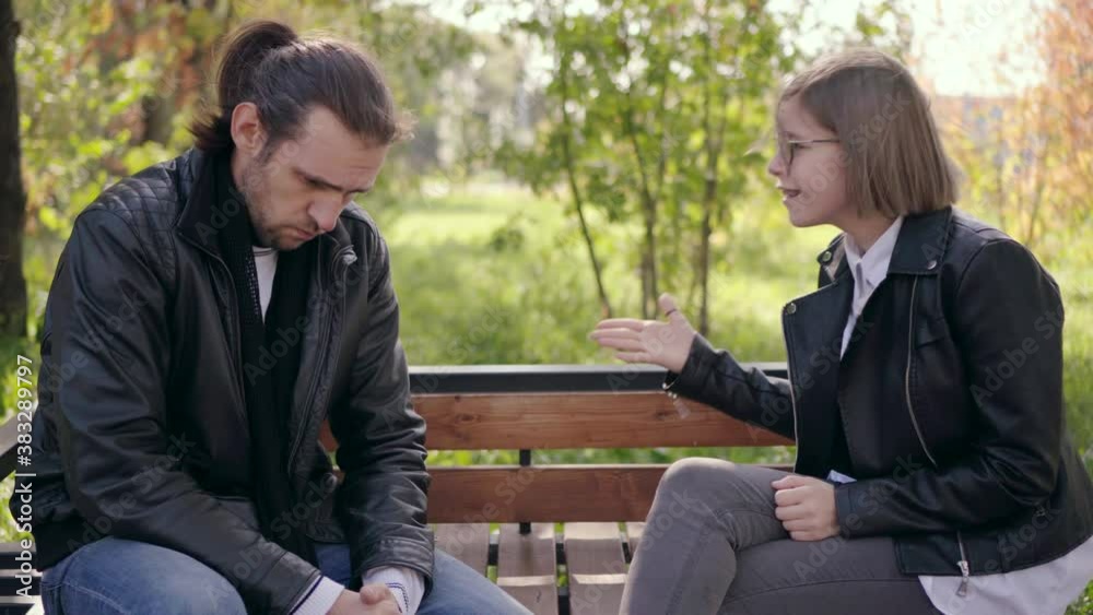 Angry girlfriend scolds and shout on her boyfriend on bench at the park. Angry girlfriend scolds and shout on her boyfriend on bench at the park.