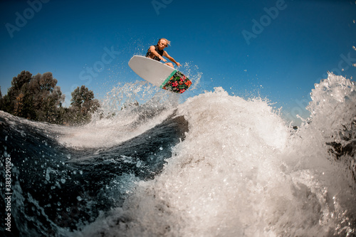 Beautiful view of man on surf style wakeboard masterfully jumping over splashing wave
