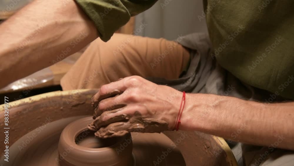 Close-up of a man potter making a clay bowl on a potter's wheel from clay
