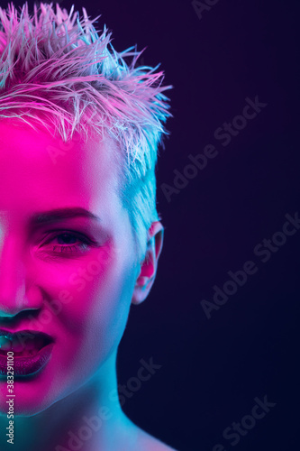 Shine. Portrait of female fashion model in neon light on dark studio background. Beautiful caucasian woman with trendy make-up and well-kept skin. Vivid style, beauty concept. Close up. Copyspace