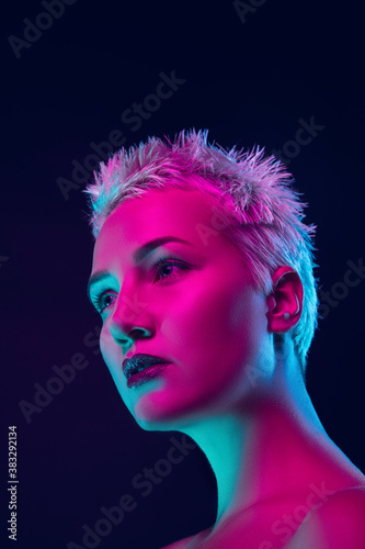Future. Portrait of female fashion model in neon light on dark studio background. Beautiful caucasian woman with trendy make-up and well-kept skin. Vivid style, beauty concept. Close up. Copyspace