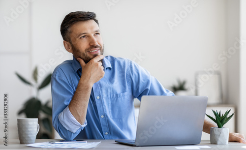 Handsome Male Entrepreneur Sitting At Workplace With Thoughtful Face Expression