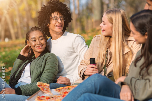 Teen african american couple having picnic with friends at park