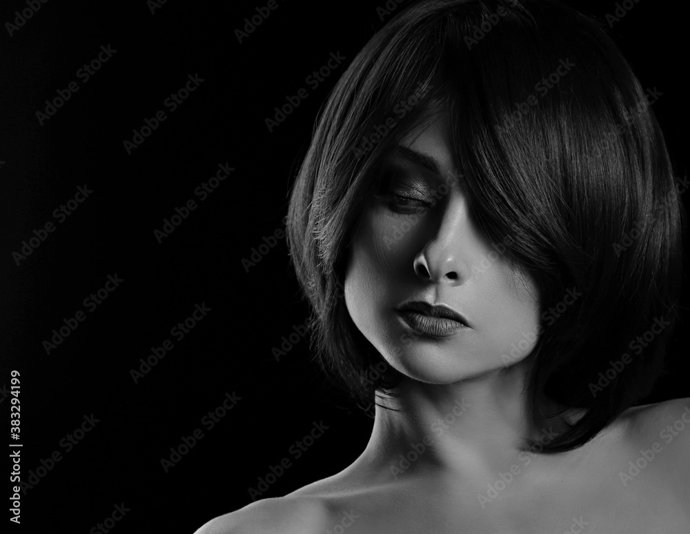 Fototapeta premium Alluring portrait of short bob hair style woman looking down on black background. Closeup art portrait.