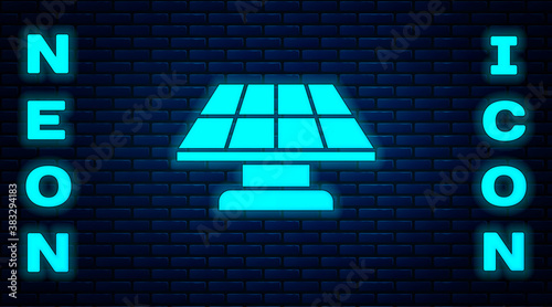 Glowing neon Solar energy panel icon isolated on brick wall background. Vector.