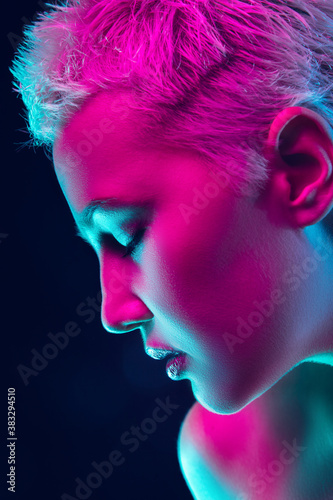 Passion. Portrait of female fashion model in neon light on dark studio background. Beautiful caucasian woman with trendy make-up and well-kept skin. Vivid style, beauty concept. Close up. Copyspace