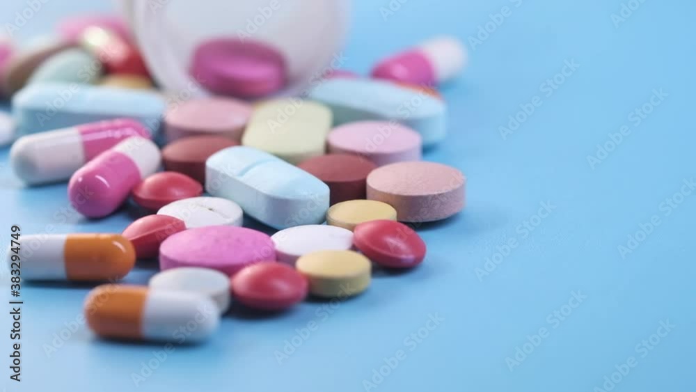close up of colorful pills spilling on blue background close up of colorful pills spilling on blue background