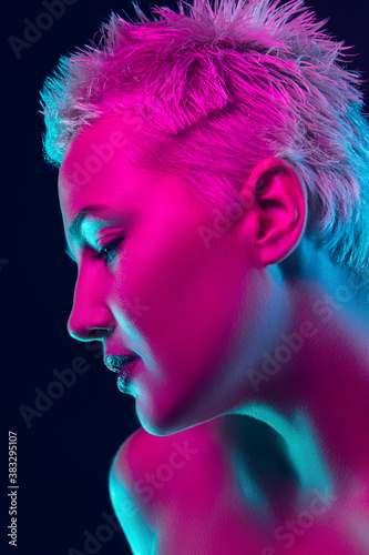 Passion. Portrait of female fashion model in neon light on dark studio background. Beautiful caucasian woman with trendy make-up and well-kept skin. Vivid style, beauty concept. Close up. Copyspace