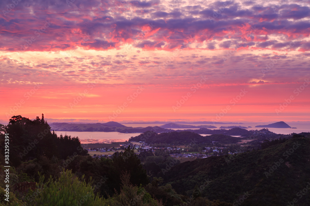 A view of Coromandel, a seaside town on the Coromandel Peninsula, New Zealand, at sunset, taken from the surrounding mountains