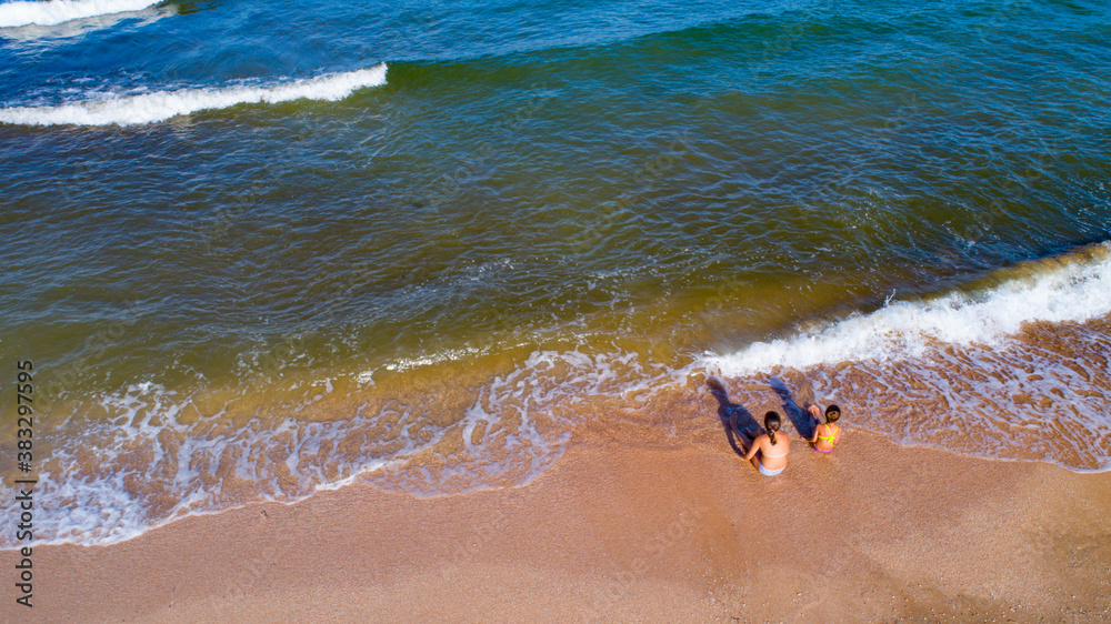 Two sisters playing with sand on the sea coast Two sisters playing with sand on the sea coast