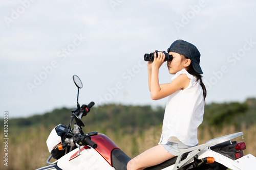 オフロードバイクに乗って双眼鏡で遠くを見る女の子