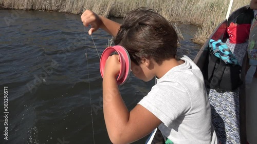 Dalyan, Turkey - 24th of September 2020: 4K Kid is learning crab fishing from the boat with fishing line
 photo