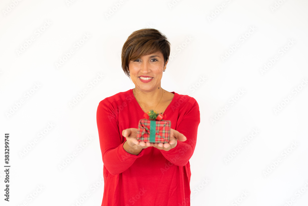 Middle age latin woman holding a christmas gift isolated on a white background smiling Middle age latin woman holding a christmas gift isolated on a white background smiling