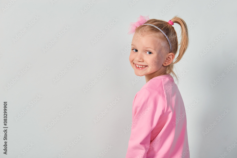 Cute girl 4-5 year old posing in studio in a pink sweatshirt Cute girl 4-5 year old posing in studio in a pink sweatshirt