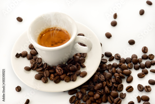 Italian espresso in white cup, steaming hot with scattered coffee beans, on white background
