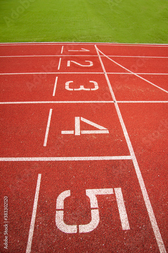 Athletic running track in a stadium with start point positions numbers one two, three, four five. No people. © Ole