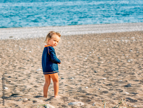 Lonely toddler girl standing on beach
