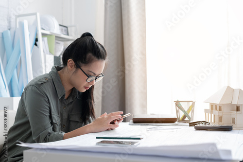 architect woman using mobile phone on desk with architectural model