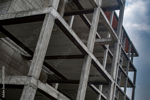 Reinforced concrete construction, load-bearing structure on cloudy sky background 