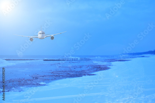 Airliner over the wintry ocean. Snow beach