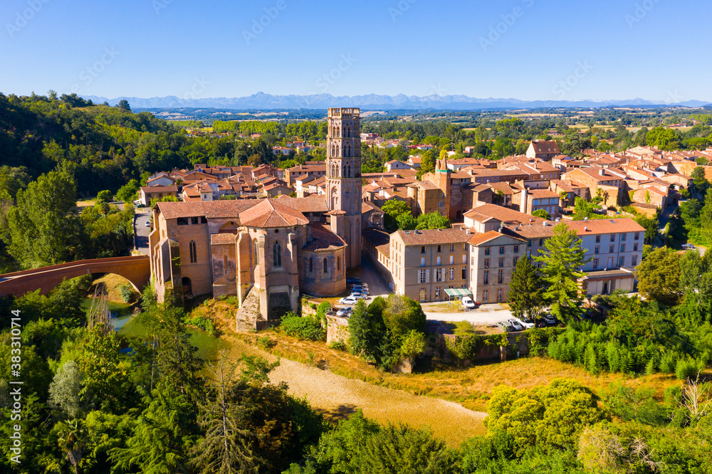 Scenic aerial view of Rieux-Volvestre town on banks of small tributary of Garonne in summer overlooking ancient Roman Catholic Cathedral, France