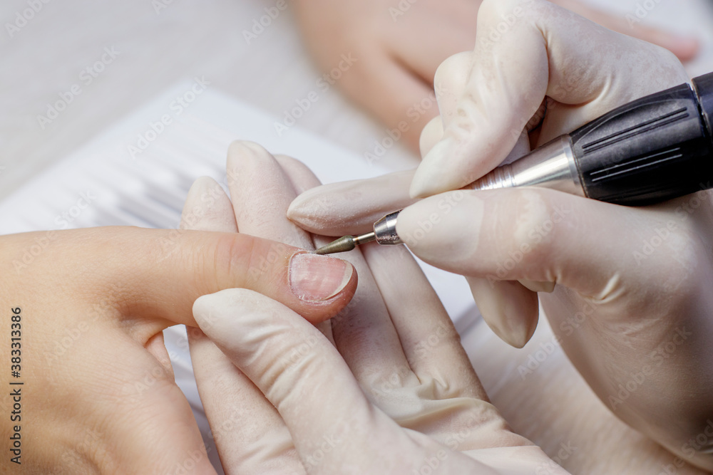 Female hardware manicure in the salon. Processing of nails with a metal conical cutter. Female hardware manicure in the salon. Processing of nails with a metal conical cutter.