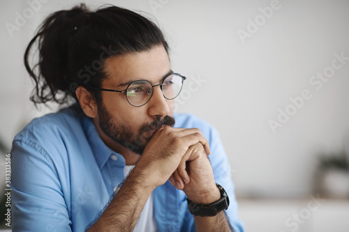 Closeup Portrait Of Pensive Millennial Indian Man In Eyeglasses Looking Away