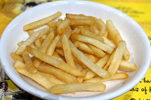 A white plate full of delicious french fries macro isolated snack top view