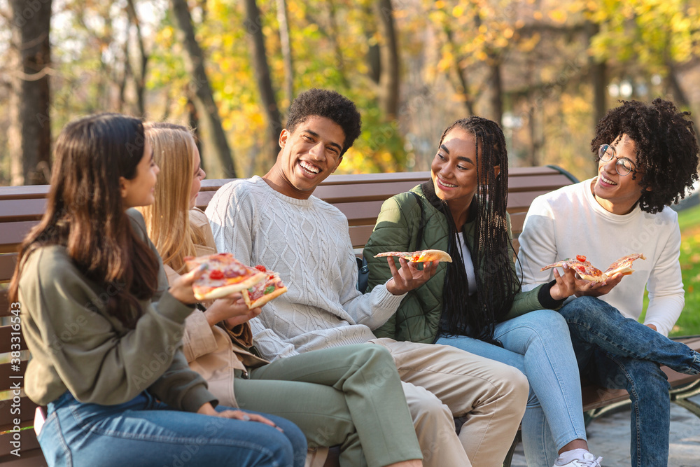 Black guy making funny jokes, eating pizza with friends - obrazy, fototapety, plakaty 