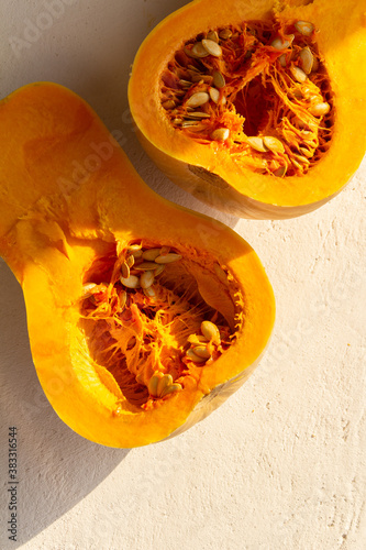 Fresh organic pumpkin cut into pieces on light concrete background