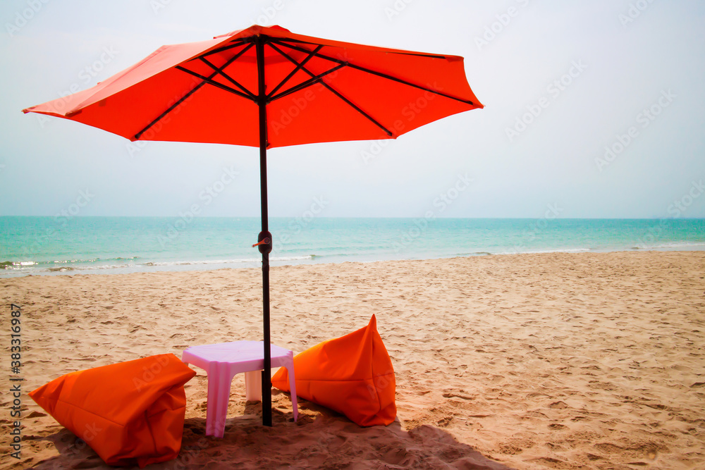 Orange umbrellas are located on the white sand beach by the sea and beautiful sky.
Cha Am, a popular tourist destination in Thailand.