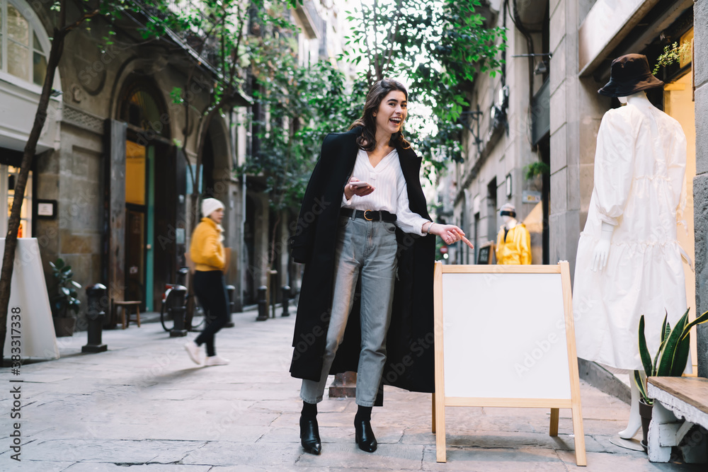 Fototapeta premium Stylish woman pointing to banner ad on street