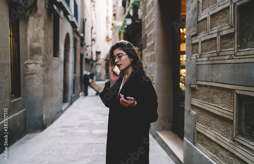 Focused woman talking on smartphone on street