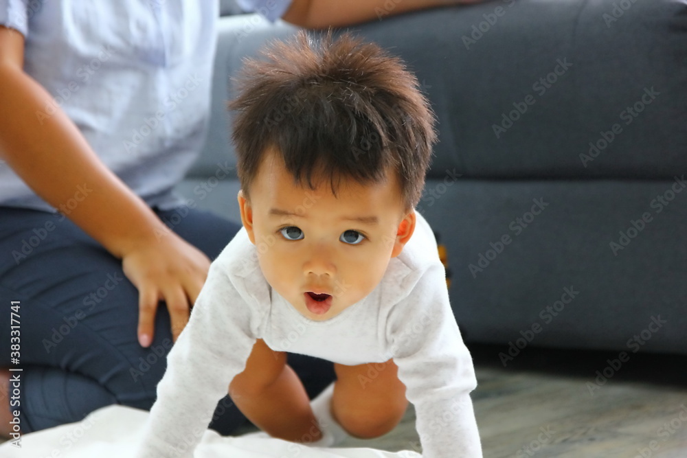 close up Asian baby crawling on the floor with mother watching over background close up Asian baby crawling on the floor with mother watching over background