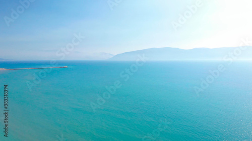 Beach umbrellas on sand washed by calm clear water of turquoise sea in Mediterranean.